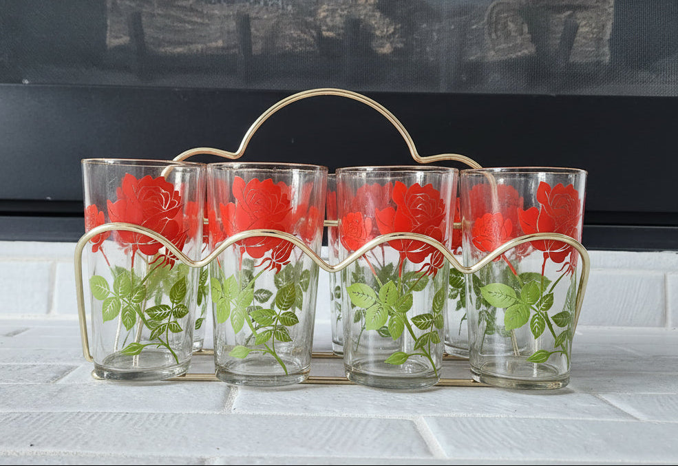 Set of six floral glass tumblers in a metal holder on a tiled surface.