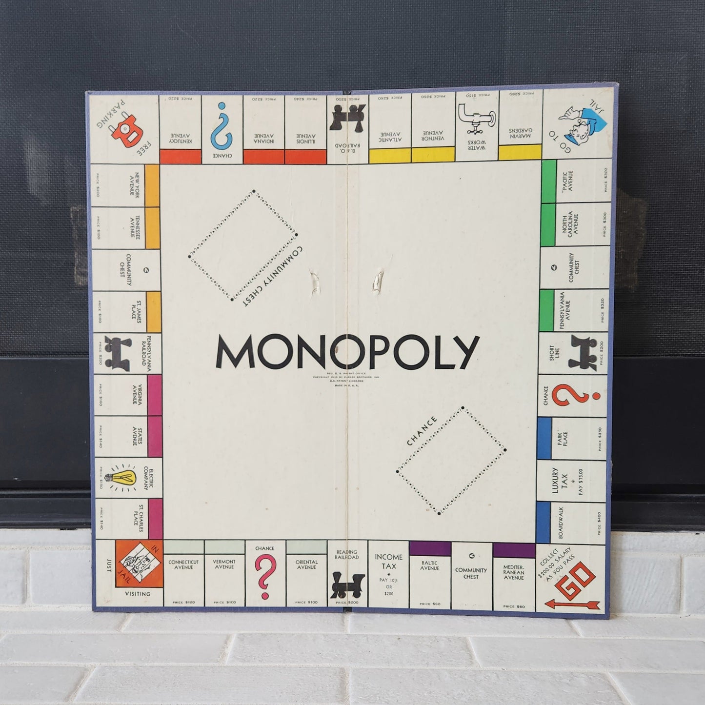 Monopoly board game on a tiled floor with a dark background