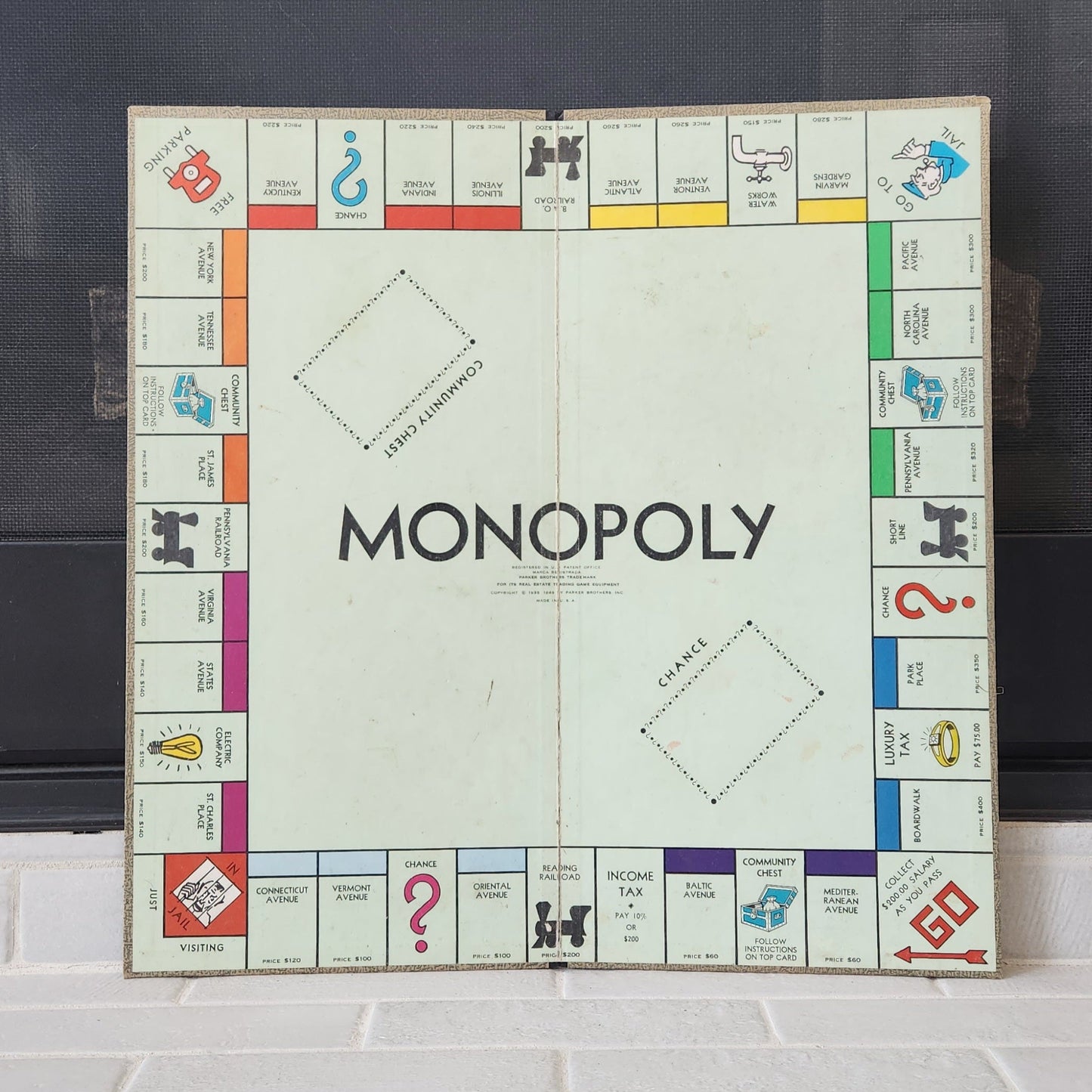 Monopoly board game on a tiled floor with a dark background